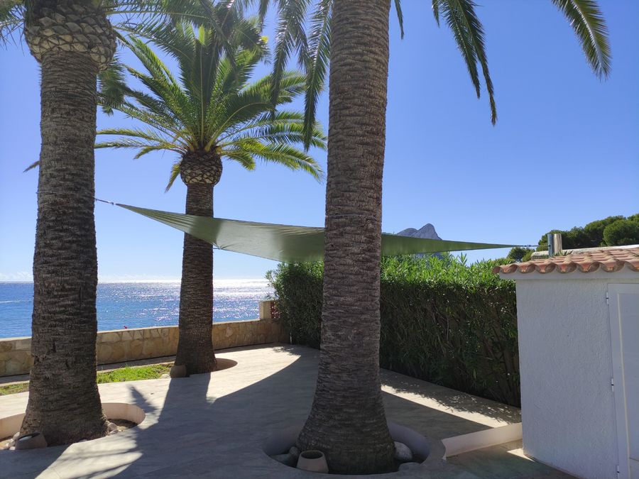 Vela de sombra triangular con palmeras y vistas al mar